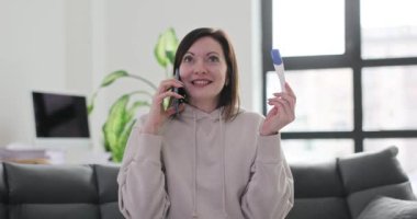 Kadın akıllı telefondan hamileliğini ilan ediyor. Hamile neşeli kadın pozitif hamilelik testi yapıyor.