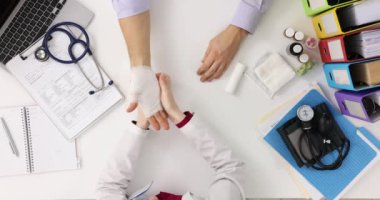 Travmatolog doktor, erkek hastaların kolunu bandajlıyor. Kliniğin üst katında. El kırığı ve burkulma tedavisi