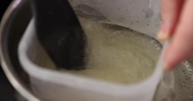 Çifte kazanda yumurta beyazı kreması pişirmek. Aşçı buharlı tencerede beyazı karıştırır.