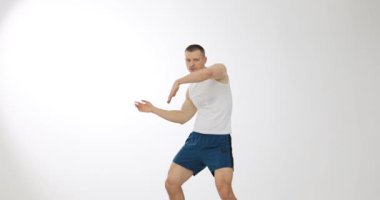 Stüdyodaki bir adamın enerjik hareketleriyle dinamik dans egzersizi. Beyaz arka planda sorunsuz dans eden bir kadın