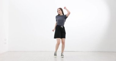 Genç ve zeki bir kadın dans ediyor ve beyaz arka planda eğleniyor. Elleriyle hareket eden, eğlenen, rahatlatan ve dans eden kız.