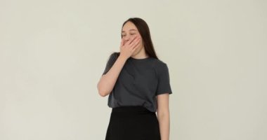 Uykulu genç kadın esniyor ve gözlerini beyaz arka plana sürtüyor. Çalışma ve dinlenme rejimi ve uykusuzluk ve yorgunluk kavramı