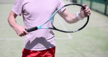 Tenisçi sahada bir maça hazırlanıyor ve raket tutuyor. Yakışıklı erkek tenisçi tenis kortunda raketle tenis topuna vuruyor.