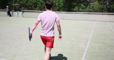 Tenis oyuncusu güneşli bir günde kortta antrenman yapar. Tenis oyunu