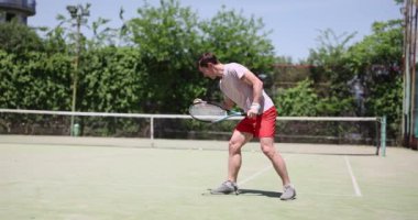 Güneşli bir günde tenis antrenmanı. Atışlarını geliştirmeye odaklanmışsın. Profesyonel olarak donanımlı tenis oyuncusu ve arka planda net tenis oyuncusu raketle tenis topuna vuruyor.