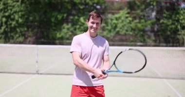 Tenisçi dışarıda atış talimi yapıyor. Tenis kortunda gülümseyen erkek tenisçi