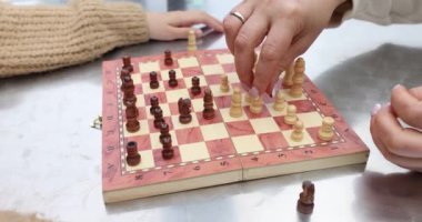 İki oyuncu tahta bir tahtada satranç oynuyorlar, strateji ve beceri gösteriyorlar. Satranç eğitimi