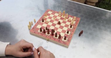Masada iki kişi satranç oynuyor. Oyuncu derin düşüncelere dalmış ve satranç tahtasındaki sonraki hamlelerin stratejisini düşünüyor.