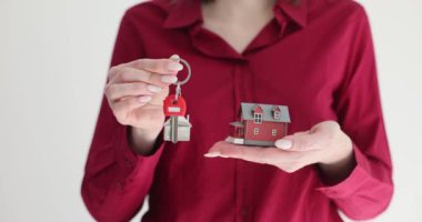 Emlakçıda evin anahtarları ve yeni evi sembolize eden bir model ev var. Kiralık konut satın almak