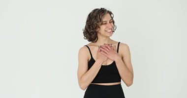 Gülümseyen kadın beyaz arka planda reverans yapıyor. Kız kibarca eğilir ve minnettarlığını gösterir.