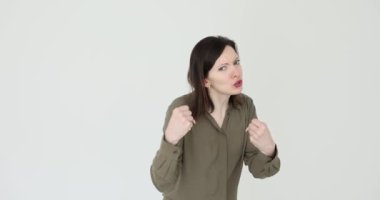 Öfke ve hüsran dolu öfkeli genç bir kadın beyaz arka planda agresif bir öfkeyle yumruğunu kaldırıyor. Öfke ve saldırganlık duyguları.