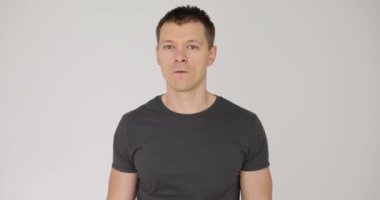 Beyaz arka planda neşeli, seksi bir adamdan küstah bir göz kırpması. Genç adam doğrudan kameraya bakıyor. Mutluluk ve göz kırparak.