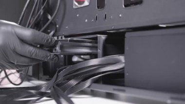 Specialist of a computer assembling workshop puts the hard drive in its place inside the case. Anonymous professional hardware workers hand in black glove close shoot.