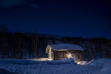 Sıcak Wintry Kayak Tatil Köyü Karlı Çatı ve Kuzey İsveç Ormanları 'ndaki açık mavi gökyüzü ile aydınlatılmış Pencereler.