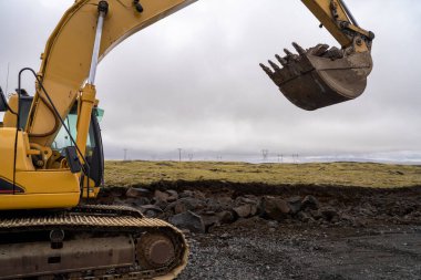 İzlanda 'nın Volkanik aktif bölgesinde kazma kovası olan kazıcı. Açık çukur kazma ve ezilmiş taşı işlemede taş kaldırma makinesi çalışıyor..