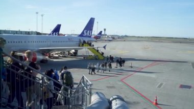 Kastrup, Danimarka - 04 Mayıs 2023: Tatildeki insanlar merdivenleri çıkmak için sırada bekliyorlar, hafta sonu için havaalanında yolcu uçakları kuyruğuna giriyorlar..