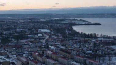 Bir Huskvarna Şehrinin Alacakaranlık ya da Şafak Vaktindeki Sersemletici Hava Manzarası, Sokak ve inşaat ışıklarıyla aydınlatılmış Güzel Bir Nüfus Alanının Sahnesi, Bir Gölün Sakin Sularına Yansıtılıyor