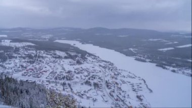 Funasdalen Köyü Timelapse, Kış Saati 'ni, kar manzaralı ormanlık araziler ve İsveç' teki donmuş göller manzaralı funasdals dağının tepesinden çeker..