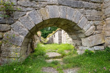 Yosun kaplı bir taş kemer, Alvastra Kloster 'ın kalbine bir göz atar. Bereketli yeşilliklerle dolu dolambaçlı yol, zamanda geri adım atmaya ve antik kalıntıları keşfetmeye davet eder..