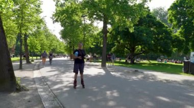 Amsterdam, Hollanda - Mayıs 2024: Vondelpark 'ta hayat dolu bir duvar halısı, bisikletçiler, koşucular ve yeşil vahadan keyif alan aylaklarla gözler önüne seriliyor.