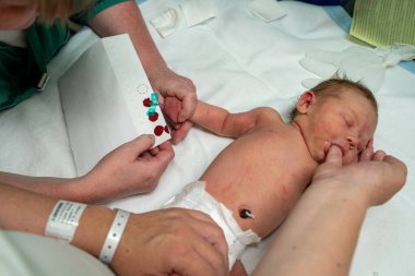 Hastanede kan testine tabi tutulan bir bebek ve bir sağlık uzmanı, ameliyatın güvenli ve hijyenik bir şekilde yapılmasını sağlıyorlar..