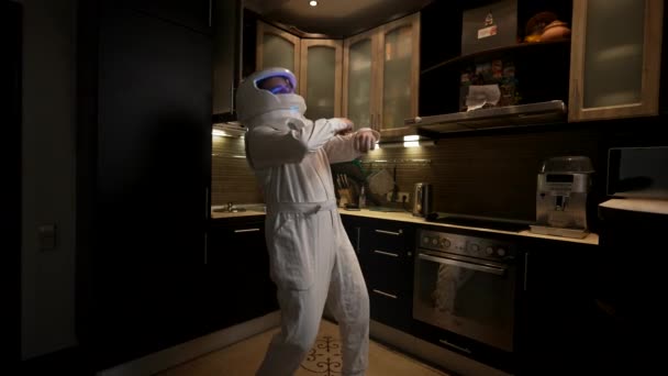 宇宙飛行士の衣装を着た男が台所で踊る 面白いクレイジー宇宙飛行士は Issへの彼の将来の使命について非常に満足しています — ストック動画