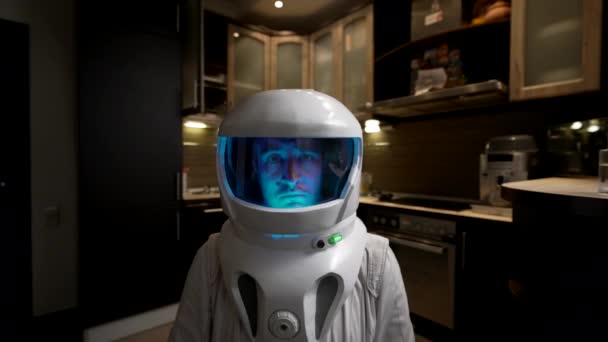 美国宇航局一位悲伤的宇航员站在厨房里 一位身穿航天服 头戴蓝灯 头戴钢盔的年轻人站在他家普通厨房的内部 — 图库视频影像