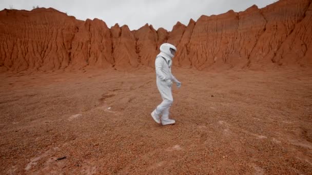 Vista Lateral Astronauta Caminando Por Una Superficie Anaranjada Planeta Desconocido — Vídeo de stock
