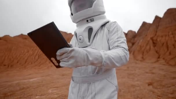 Seorang Astronot Dengan Pakaian Pelindung Berjalan Dengan Tablet Permukaan Planet — Stok Video