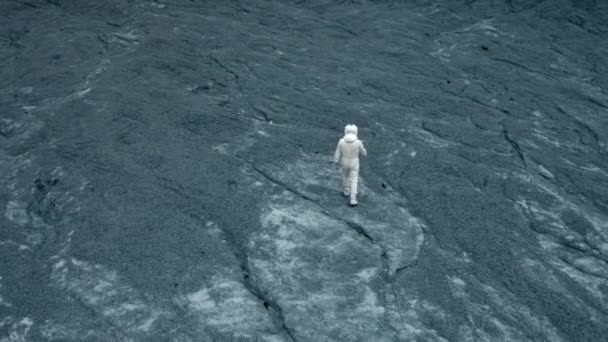 宇宙飛行士と未知の惑星の灰色の表面 宇宙飛行士の衣装の認識できない男はクレーターの境界に行きます — ストック動画