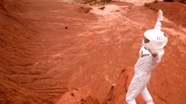 Zaferi kutlayan bir astronot kraterin kenarındaki bir tepede duruyor. Beyaz takım elbiseli ve koruyucu kasklı astronot kollarını sallıyor ve kazananın hareketlerini gösteriyor.