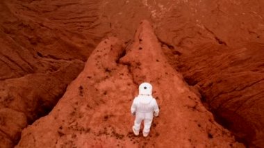 Mutlu bir astronot krater tepesinin kenarına yaklaşıyor ve sevinçten zıplıyor. Beyaz takım elbiseli ve kasklı bir astronot kollarını mutlulukla sallıyor ve Mars 'ın güzel manzarasına bakıyor..