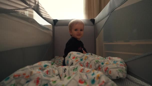 可爱的小男孩在游乐帐篷的床垫上爬行 看着镜头 金发碧眼的幼儿周末早上都呆在镇上房子的特写慢镜头里 — 图库视频影像