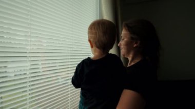 Anne oğlunu kollarına aldı ve pencerenin perdelerinden dışarı baktı. Kadın ve küçük çocuk hafta sonunun erken saatlerinde yatak odasında iyi eğlenceler.