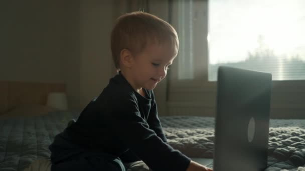 甘い幼児は 現代のラップトップのキーボードにテキストを入力することを学びます 好奇心旺盛な子供は 寝室のクローズアップスローモーションでガジェットを使用する新しいスキルを取得します — ストック動画