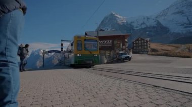 Yolcu treni Highland 'daki istasyona varır. İsviçre 'de mavi gökyüzünün altında buzlu zirveleri olan toplu taşıma ve dev dağlar