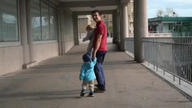 Oğlu ve kızı olan mutlu baba, antik binanın gözlem güvertesinde yürüyor. Çocuklu bir adam kameraya dönüp ağır çekimde gülümsüyor.