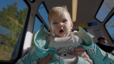 Sevimli tombul bir kız, pencerenin yanında ana kollarında oturuyor trenle seyahat ediyor. Sarışın bebek kameraya bakıyor Highland 'a doğru esniyor.