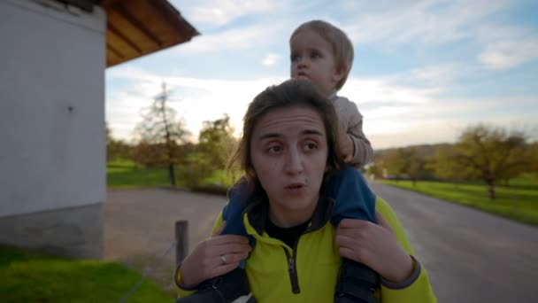 Kíváncsi Kisgyerek Anya Vállán Körülnéz Hordozza Kisfiút Sétál Úton Vidéken — Stock videók