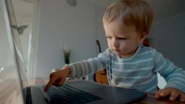 Modern dizüstü bilgisayarın klavyesine odaklanmış sarışın çocuk yazıları. Yürüyen çocuk, masadaki yavaş çekimde modern teknolojiyi incelemeyi seviyor.