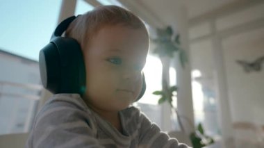 Tombul, kulaklıklı, parlak güneş ışığında dizüstü bilgisayarda oturan tipler. Sevimli küçük çocuk yakın çekim aletleri kullanma tecrübesi kazanıyor.