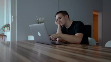 Depresyondaki adam, odasındaki ahşap masada oturarak dizüstü bilgisayarla çalışmaya devam etmeye çalışıyor. Erkek serbest çalışan, klavyede kendini kötü hisseden tuşlara basar.