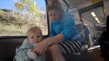 Annem, İsviçre dağlarına giderken trende ayakta durmayı öğrenen küçük kızın elini tutuyor. Mutlu kadın ve tatlı bebek tatilin tadını çıkarın.