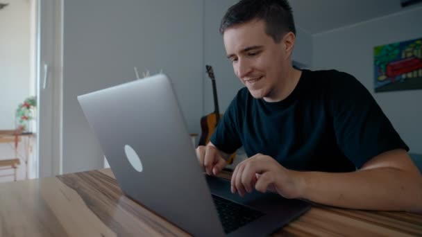 快乐的男人喜欢在现代笔记本电脑上上网工作 男性自由职业者在家中坐在木制桌旁慢动作装置键盘上报告 — 图库视频影像