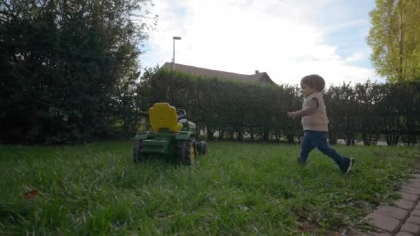Doce Criança Corre Gramado Verde Para Sentar Brinquedo Trator Menino — Vídeo de Stock