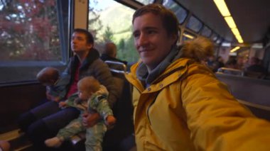Trenle İsviçre 'ye yapılan eğlenceli seyahatin video kaydı. Küçük çocuklu baba, kız, erkek ve arkadaş oturmuş tren vagonunun penceresinde oturuyor.