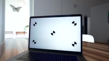 Erkek serbest çalışan dizüstü bilgisayar başında beyaz renkli ekranla ahşap masada oturmaya başlar. İnsan evde modern elektronik cihazlar kullanıyor.