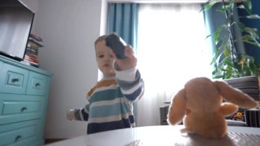 Şirin küçük çocuk evde rahat bir odada vakit geçirirken masada oturuyor ve küçük arabasıyla oynuyor.