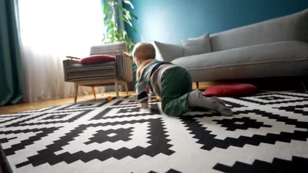 在舒适的客厅里呆着 回头看那个穿着休闲装 趴在地板上玩汽车玩具的难以辨认的男孩 — 图库视频影像