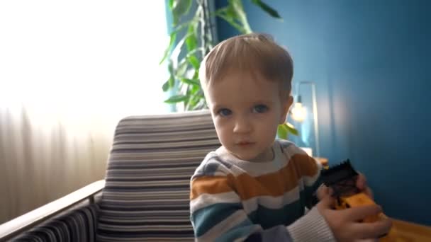 Glad Småbarn Tittar Direkt Kameran Medan Sitter Mysig Fåtölj Vardagsrummet — Stockvideo